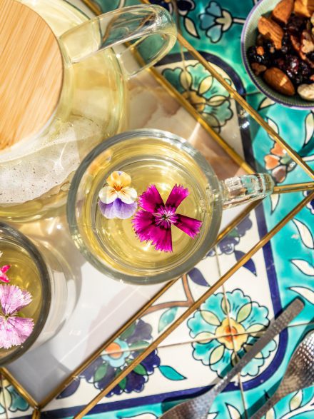 A cup of herbal tea with edible flowers on a colorful tray at Flora Valley Boutique Hotel, Ein Kerem, Jerusalem – a luxurious hospitality experience